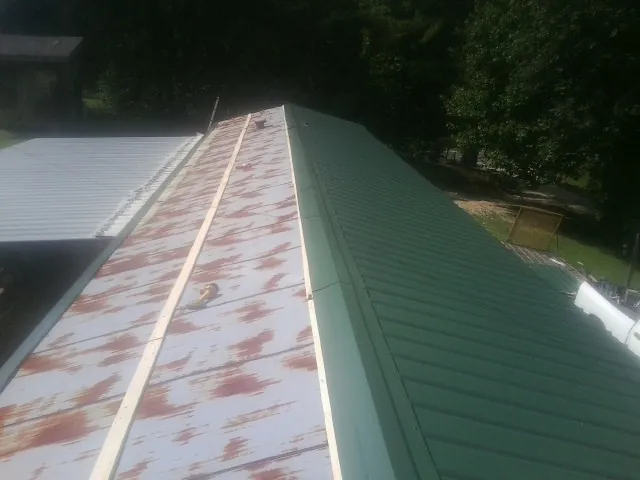 Old rusted panels beside newly installed green metal roofing — Wind Damage Roof Repair by Roofing Brothers in Swaledale