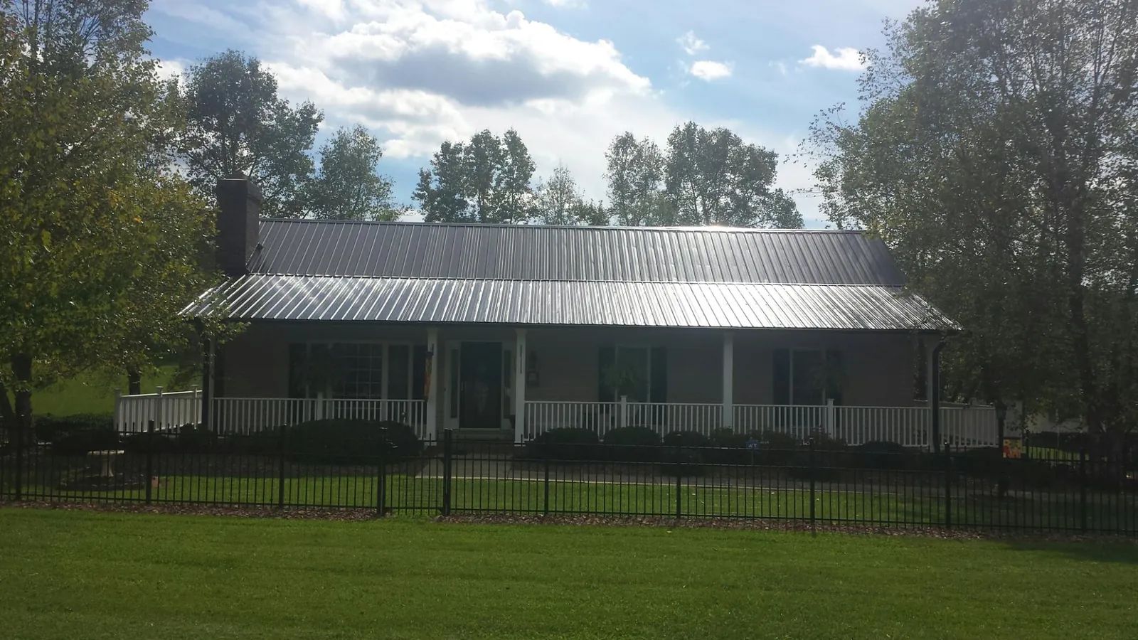 Gray metal roof on a brick ranch with a full width front porch — Gutter Guard Installation work by our crew in Swaledale