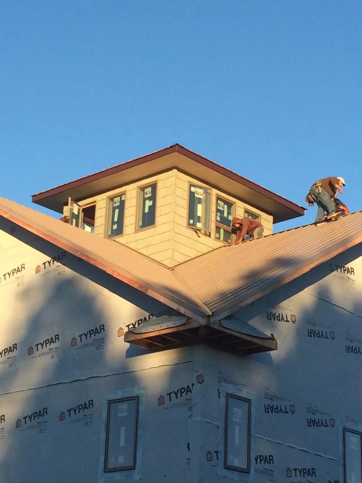 Roofers working around a rooftop cupola on a new metal roof at sunset — Roof Waterproofing in Swaledale by Roofing Brothers